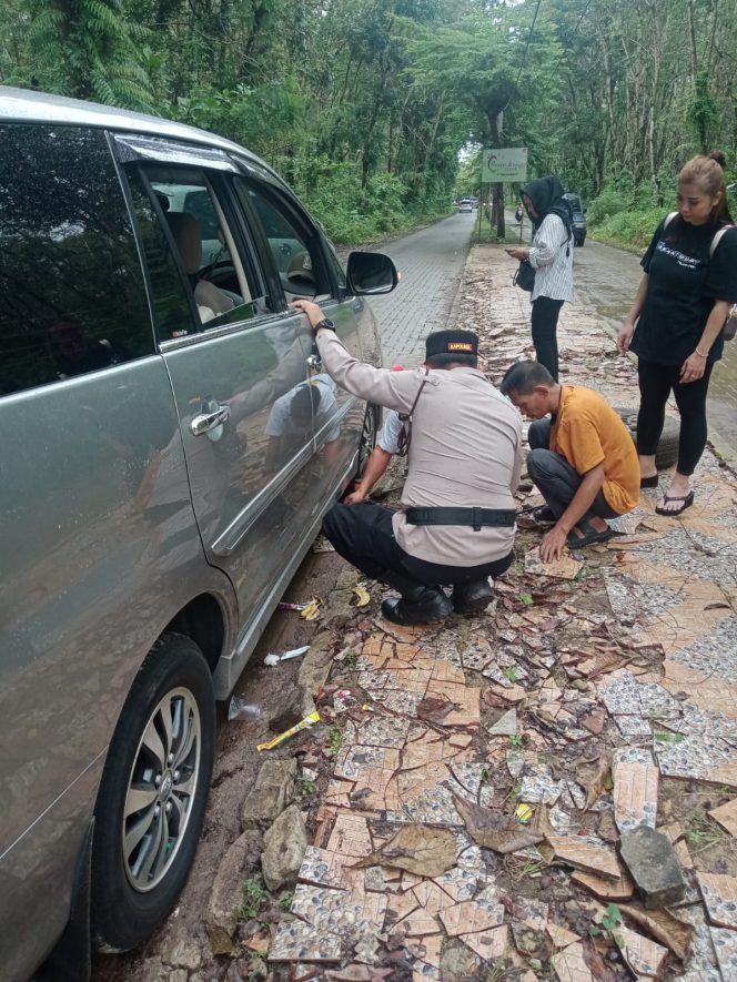 
					Foto. Kapolsek Malingling saat bantu wisatawan mengganti ban mobil