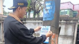 Salah seorang pegawai Perumdam Tirta Berkah yang sedang memasang stiker promo perumdam